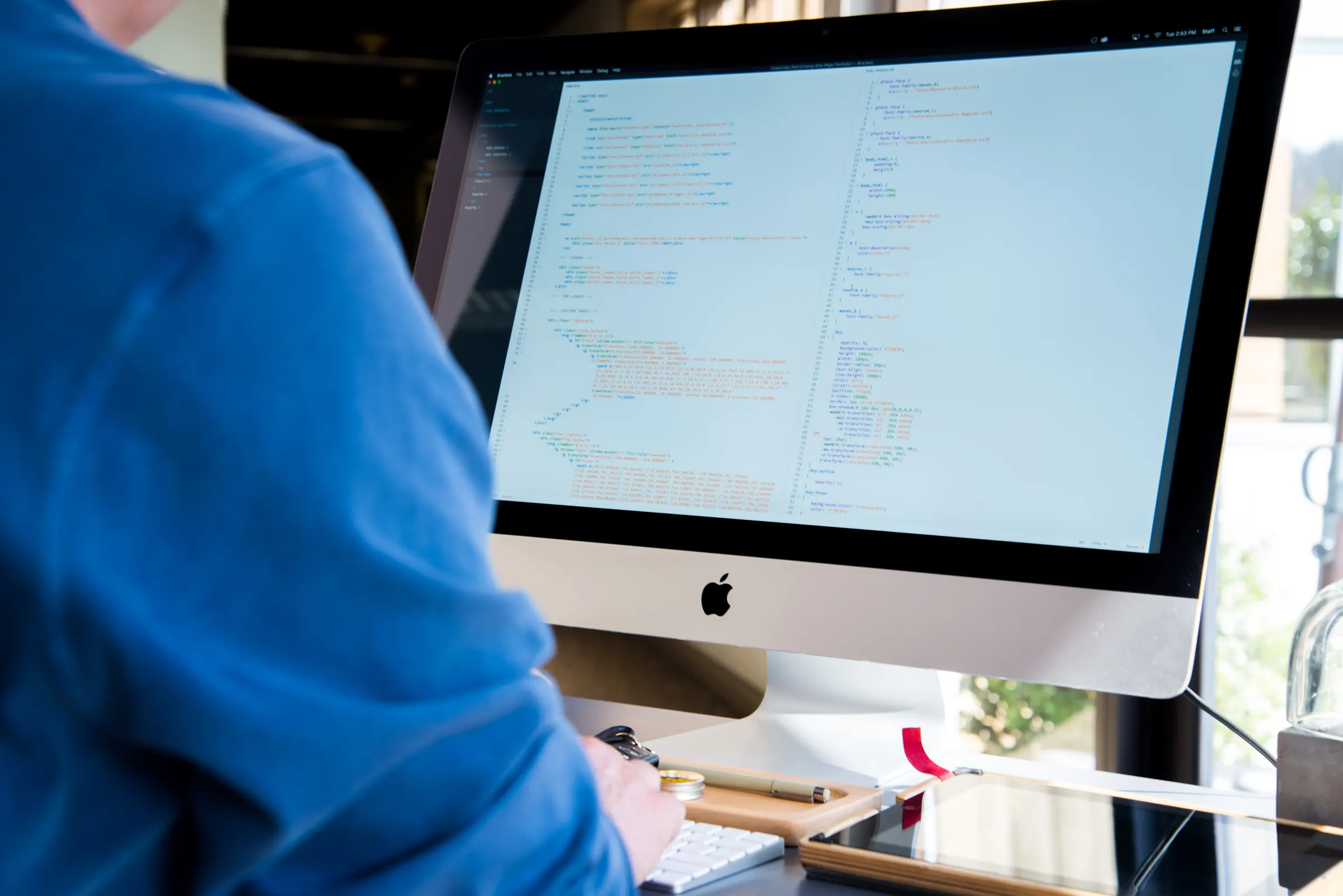 A developer at a desktop computer with code on screen.